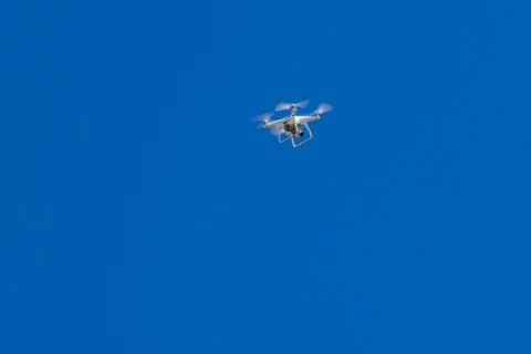 Quadcopter drone with the camera hovering in blue sky Stock Photos