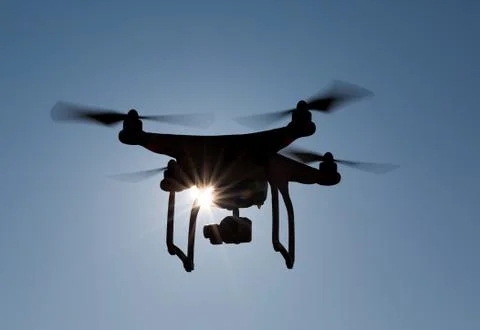 Quadcopter drone flying in front of the sun Stock Photos