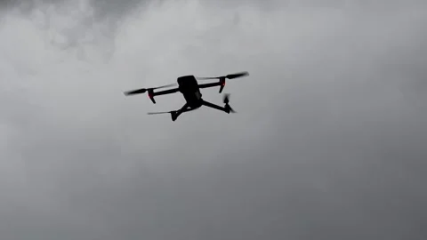 Quadcopter drone hovering and flying in dark cloudy overcast sky recorded in Stock-Footage 343458844