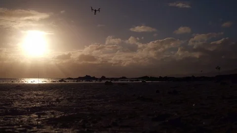 Quadcopter drone hovering over the beach during sunset Stock Footage 105418413