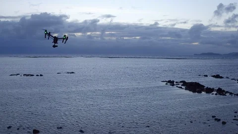 Quadcopter drone hovering over the sea during sunset Stock Footage 105417982