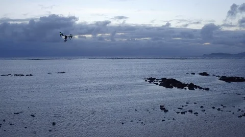 Quadcopter drone hovering over the sea during sunset Stock Footage 105418014