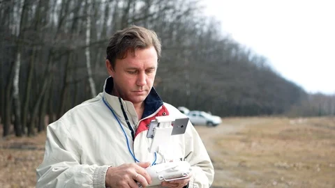 Quadcopter drone operator man adjusts radio control and telemetry in flight Stock Footage 107807731