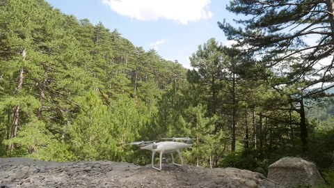 Quadcopter drone taking off from the ground and flying away in the forest Stock Footage