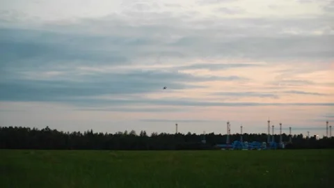 The quadcopter flies in the evening sky over the field. Stock Footage 139490380