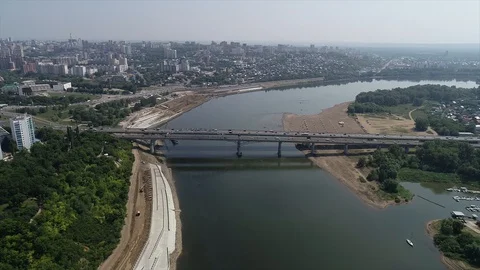 Quadcopter flies high above the river towards bridge and city in the distance Stock Footage 127893392