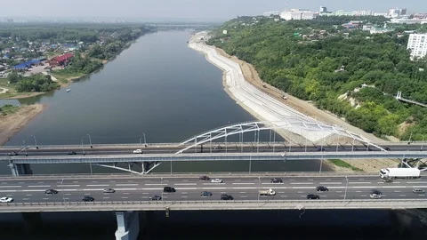 Quadcopter flies over the river and away from the bridge leading to the city. Stock Footage 130008640