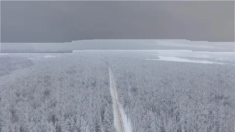 The quadcopter flies over the snow-covered pine forest and the road. Panorama Stock Footage 103231507