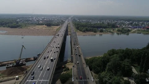 Quadcopter flying over the bridge towards the river and the sandy city beach. Stock Footage 127893387