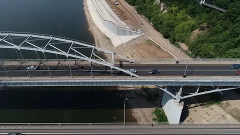 Quadcopter flying parallel to the bridge with two-way traffic over the river. Stock Footage 127893378