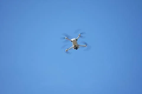 A quadcopter hovering against a cloudless blue sky Stock Photos