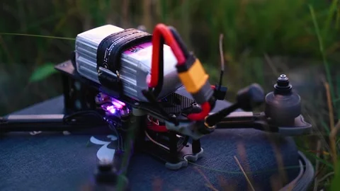 The quadcopter lies in the grass and its fans are rotating. Close-up Stock Footage 139490130