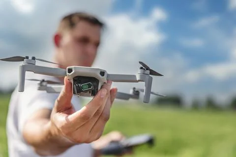 A quadcopter operator with a remote control out of focus holds a drone in front Stock Photos
