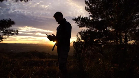 Quadcopter pilot controls his drone, shooting at sunset Stock Footage 119713191