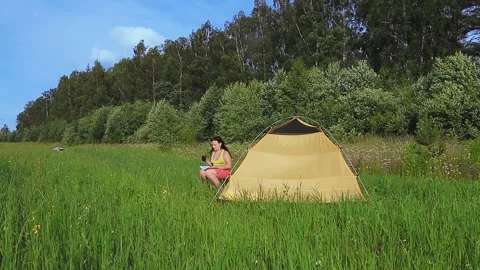 A quadcopter with a tracking function flying over a tent in which a woman is Video stock 136119418