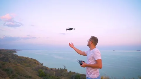 Quadrocopter flies over the man's head and lands on his hand. Slow motion in 4K. Stock Footage 93996464