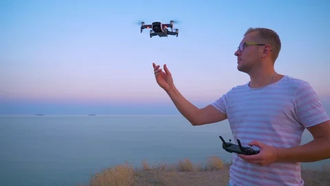 Quadrocopter flies over the man's head and lands on his hand. Slow motion in 4K. Stock Footage 93996745