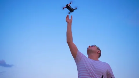 Quadrocopter flies over the man's head and lands on his hand. Slow motion in 4K. Stock Footage 93997145