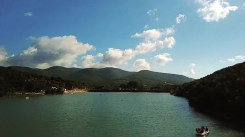 Quadrocopter rises above the lake view of the mountains catamarans on the water Stock-Footage 104701255