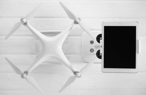 Quadrocopter, tablet and remote control on a white wooden background Stock Photos
