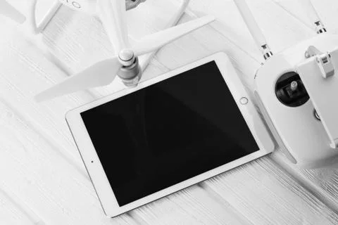 Quadrocopter, tablet and remote control on a white wooden background Stock Photos