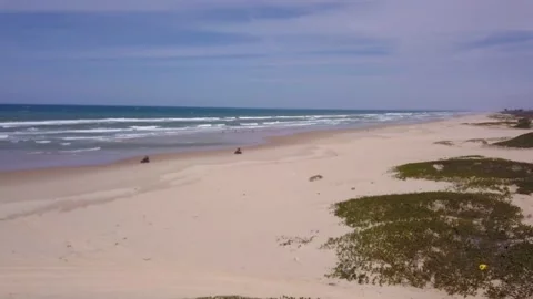 Quads driving along sandy beach, ocean waves crashing behind Stock Footage 208937342