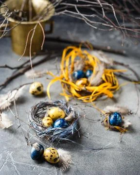Quail easter eggs with feathers in nest on brown table with copy space. Foto stock