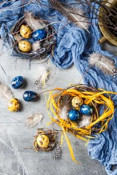 Quail easter eggs with feathers in nest on brown table with copy space. Foto stock