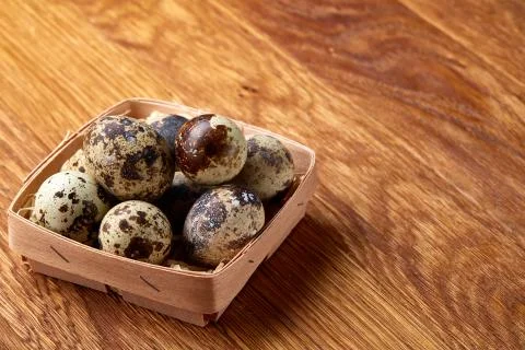 Quail eggs in a box on a rustic wooden background, top view, selective focus. Stock Photos