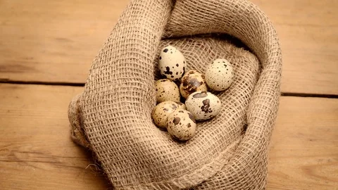 Quail eggs in burlap textile at old wooden table Video stock 120871271
