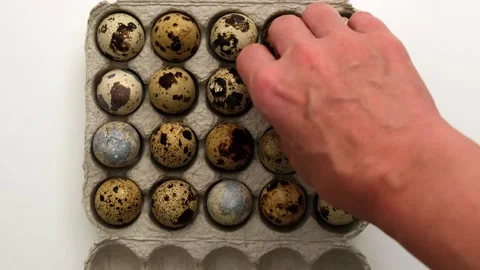 Quail eggs in cardboard packaging on white background. Woman hand takes one egg Stock-Footage 243299644
