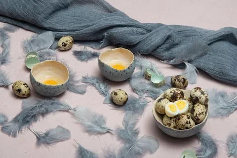 Quail eggs in ceramic vases, gray feathers on the table, easter still life, Stock Photos