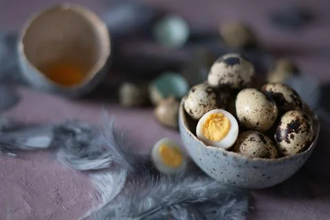 Quail eggs in ceramic vases, gray feathers on the table, easter still life, Stock Photos