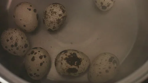 Quail eggs cooking on a boiled water inside of an stainless steel pan on a gas Stock Footage 61782558
