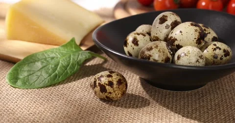 Quail eggs in a dark plate on a light background. organic food close up Stock Footage 242490700