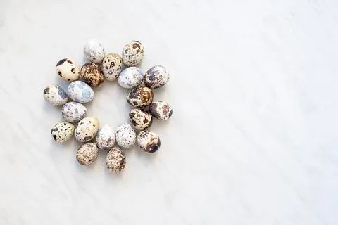 Quail eggs on a marble surface in the form of a round pattern Stock Photos