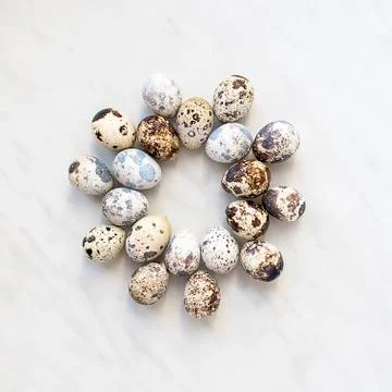 Quail eggs on a marble surface in the form of a round pattern Foto stock