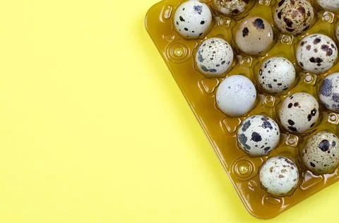Quail eggs in a package on a yellow background Stock Photos