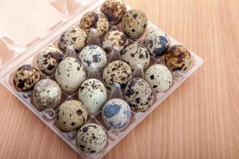 Quail eggs in transparent plastic container on wooden table Foto stock