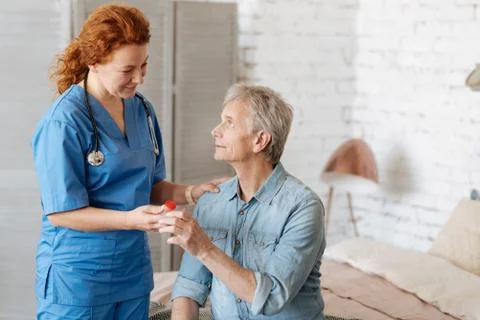 Qualified capable doctor assisting feeble man at home Stock Photos