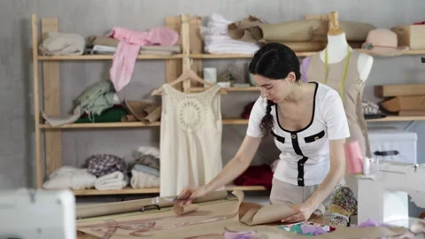 Qualified dressmaker stands in a sewing workshop and cuts with scissors the Video stock 346131675