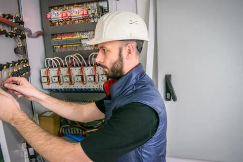A qualified engineer works in an electrical panel. Worker repairs high-voltag Stock Photos
