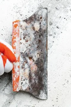 Qualified plasterer in glove using an old spatula and scrapes concrete wall Stock Photos