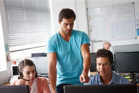 Quality control. A handsome man standing and pointing at a computer while two Stock Photos