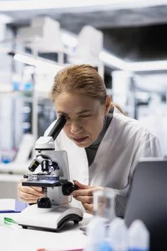 Quality control inspector in lab checking product for defects using microscope Stock Photos