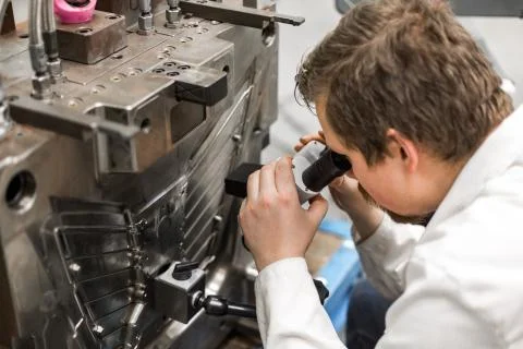 Quality engineer checks deficiencies on the injection mold by a microscope Stock Photos