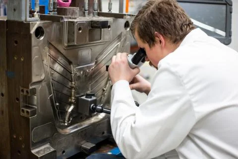 Quality engineer checks deficiencies on the injection mold by a microscope Photos
