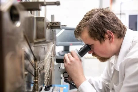 Quality engineer checks deficiencies on the injection mold by a microscope Stock Photos