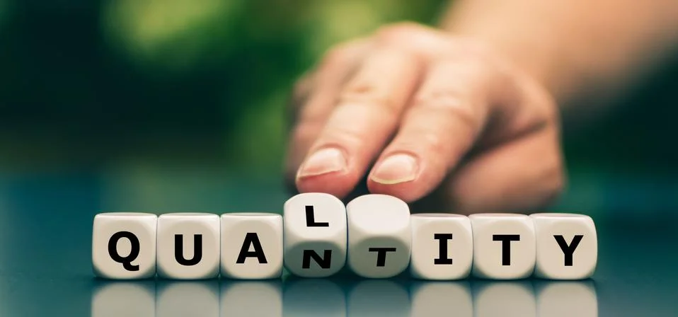 Quality instead of quantity concept. Hand turns dice and changes the word "qu Stock Photos