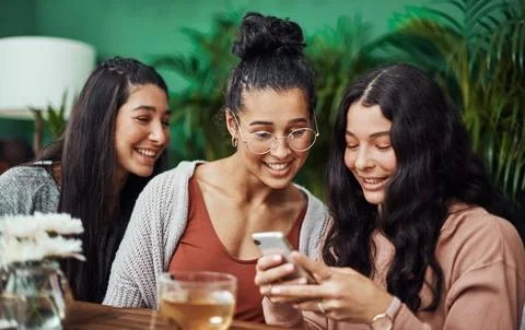 Quality time keeps us connected. young sisters using a smartphone together at a Stock Photos